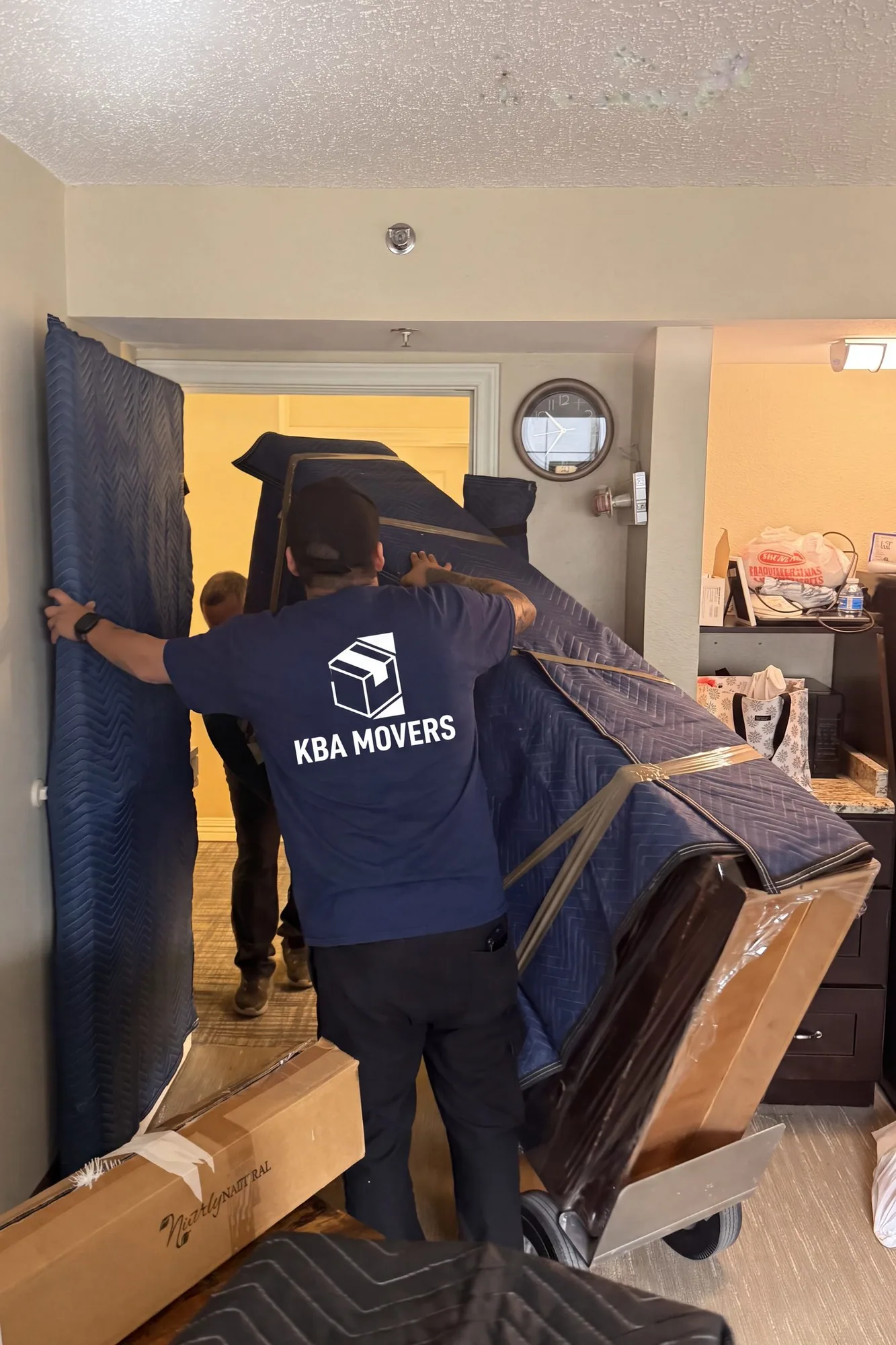 Mover maneuvering a blanket-wrapped item through a doorway