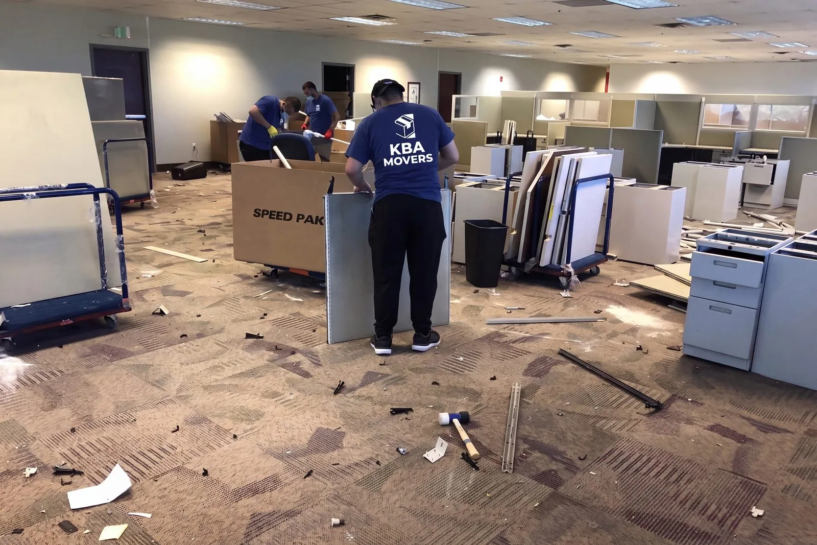 Crew clearing dismantled office furniture and debris during a cleanout