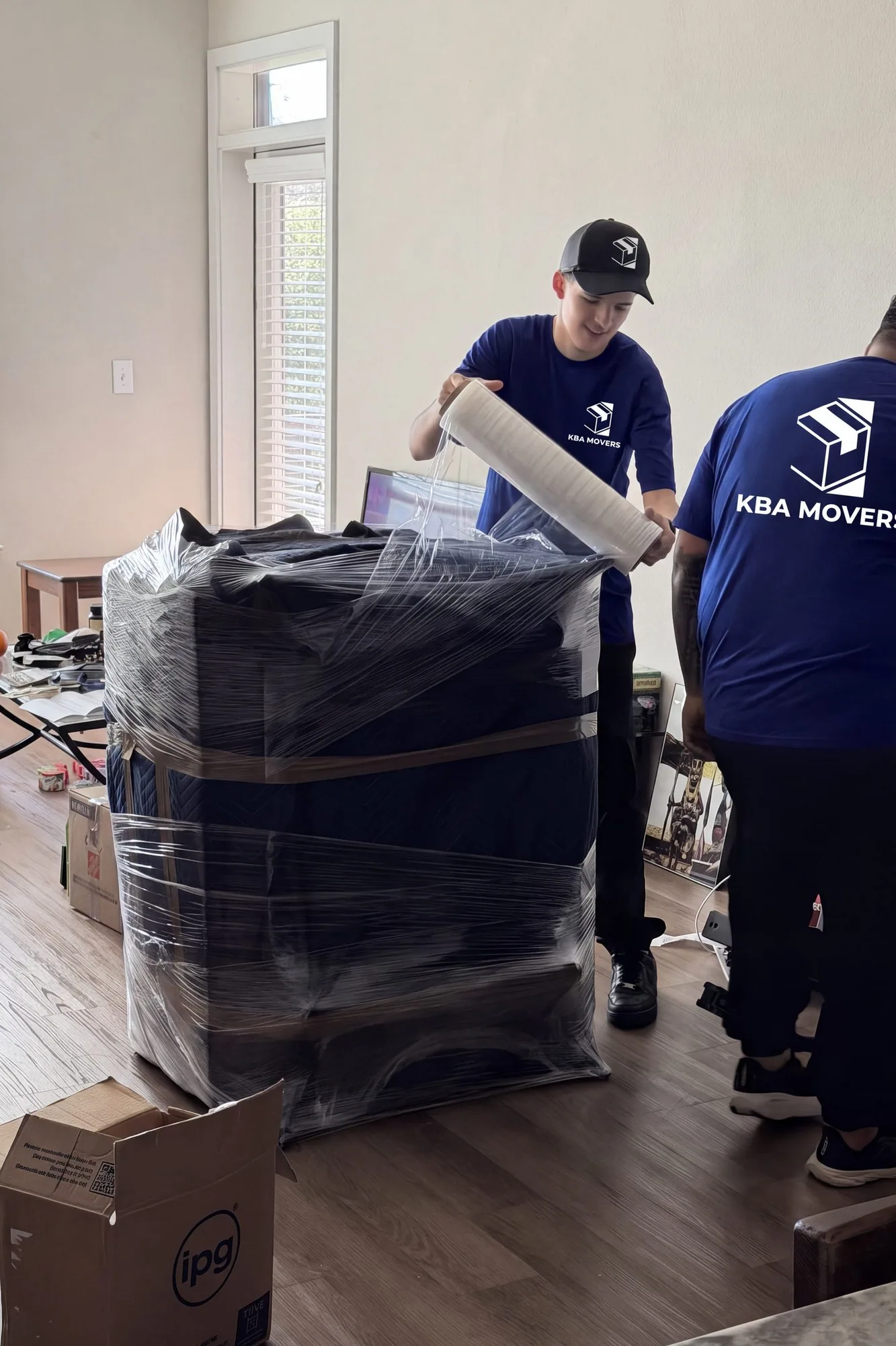 Mover wrapping a stacked load of furniture in protective plastic before a move